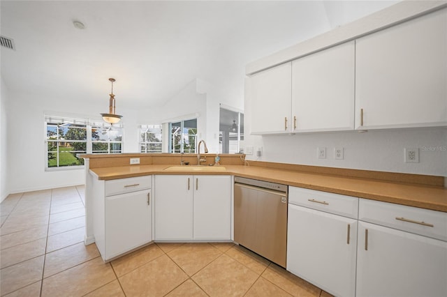 kitchen featuring light tile patterned floors, stainless steel dishwasher, white cabinets, a sink, and a peninsula