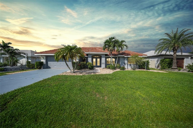 mediterranean / spanish-style home with a garage, concrete driveway, stucco siding, a tile roof, and a front yard