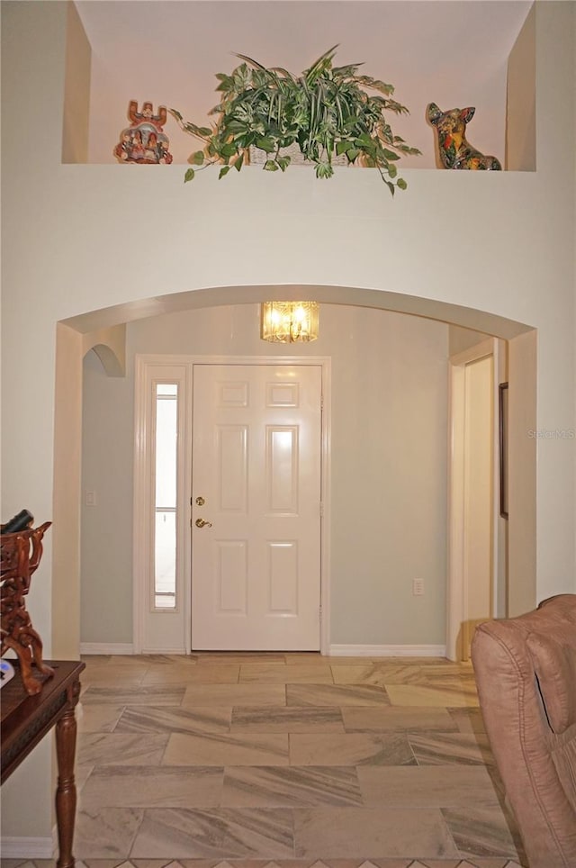 foyer entrance featuring lofted ceiling, light tile patterned flooring, and a chandelier