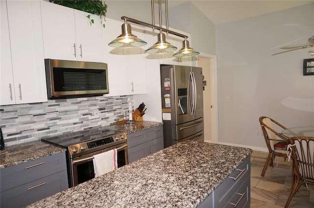 kitchen with decorative backsplash, stainless steel appliances, dark stone countertops, and white cabinetry