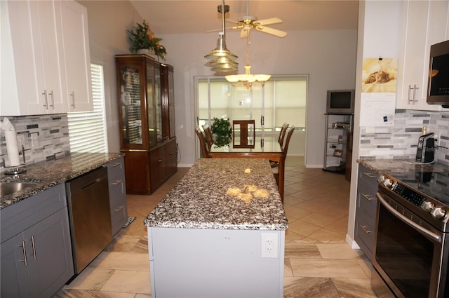 kitchen featuring decorative backsplash, white cabinets, light tile patterned flooring, a center island, and stainless steel appliances