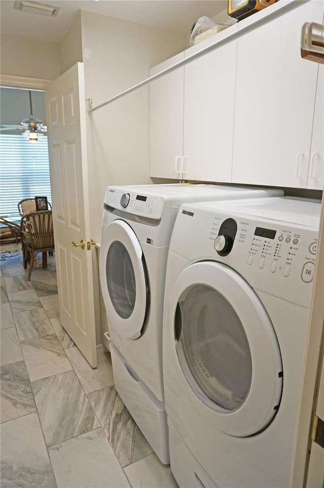 clothes washing area with ceiling fan, washing machine and clothes dryer, cabinets, and light tile patterned floors