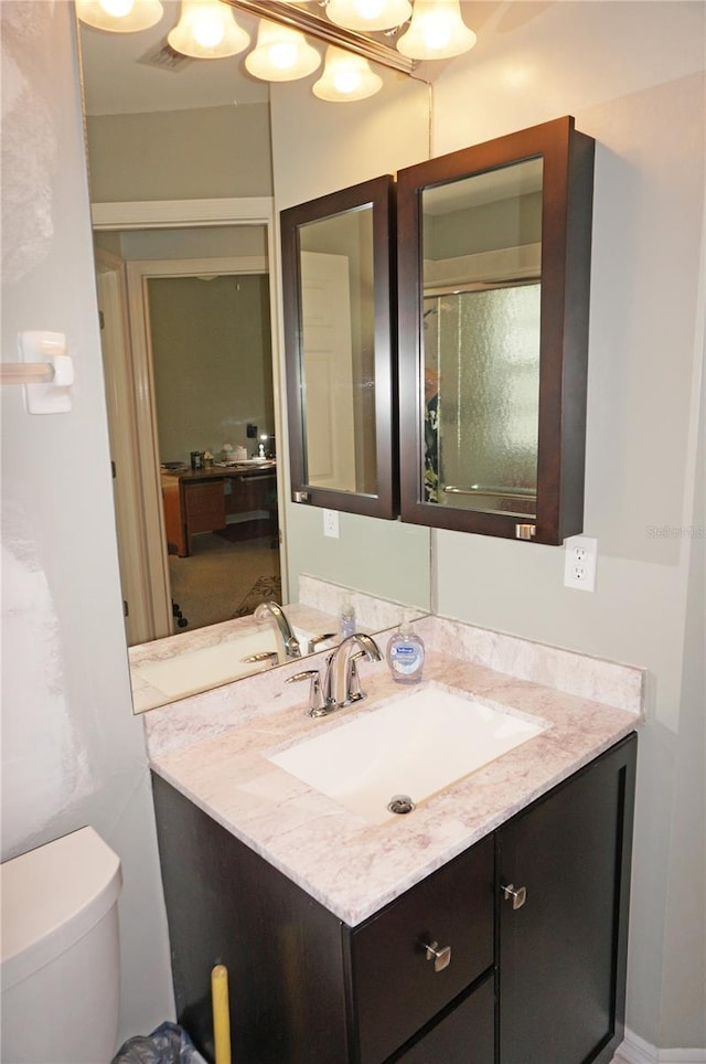 bathroom featuring toilet, vanity, and an enclosed shower