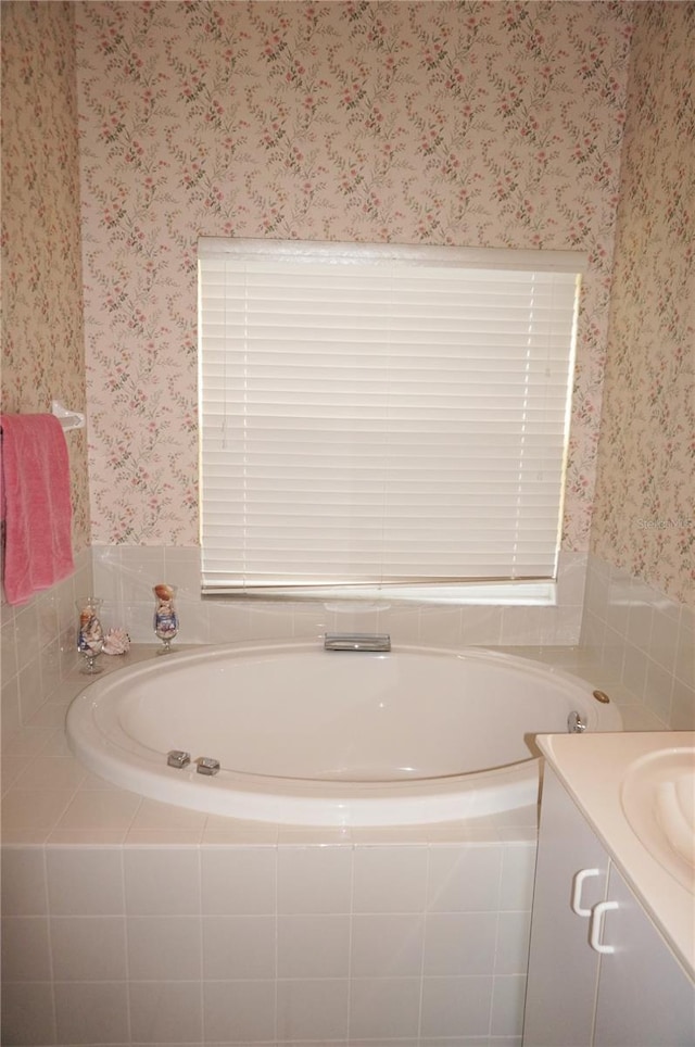 bathroom with tiled tub and vanity