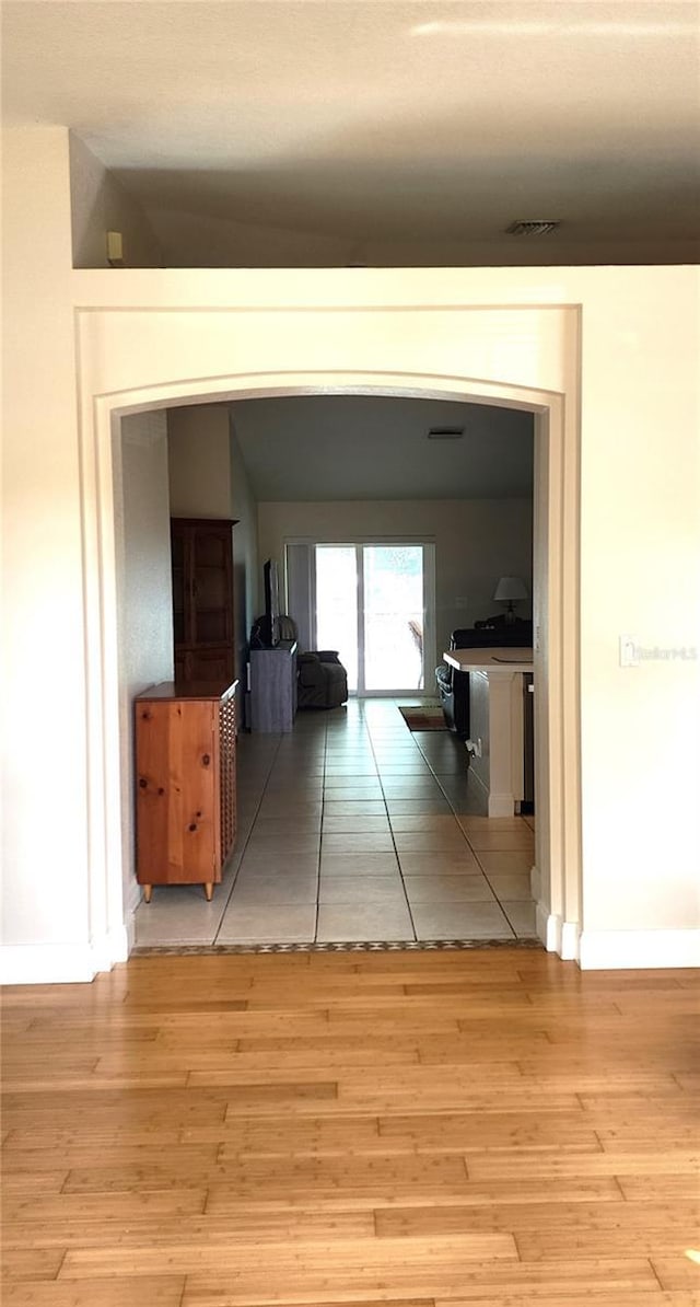 hall with visible vents, baseboards, and wood finished floors