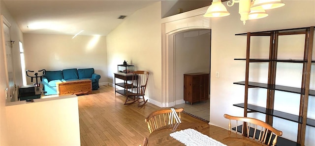 interior space with a chandelier, wood finished floors, visible vents, and baseboards