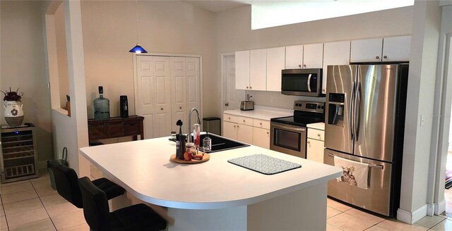 kitchen featuring wine cooler, stainless steel appliances, a sink, white cabinets, and light countertops