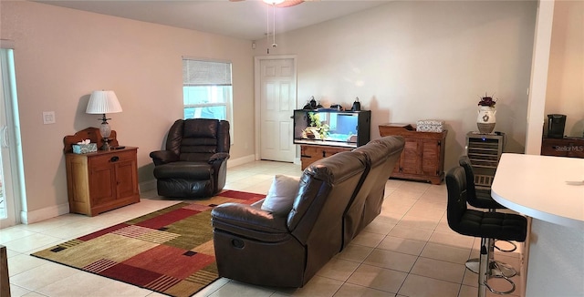 living area with light tile patterned floors, baseboards, and a ceiling fan