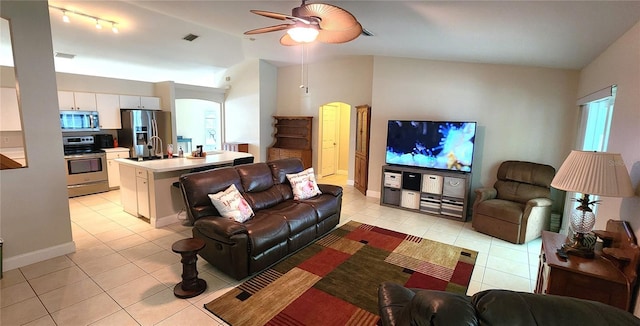 living area featuring arched walkways, visible vents, vaulted ceiling, and light tile patterned floors