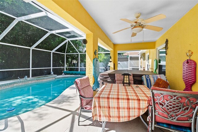 pool with a patio area, glass enclosure, and a ceiling fan