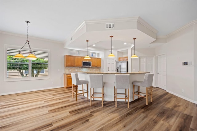 kitchen featuring light hardwood / wood-style floors, appliances with stainless steel finishes, tasteful backsplash, and a breakfast bar