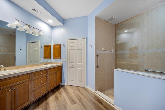 bathroom with a shower with door, hardwood / wood-style flooring, and dual bowl vanity