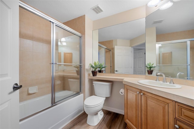 full bathroom with hardwood / wood-style flooring, toilet, shower / bath combination with glass door, and vanity