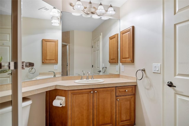 bathroom featuring a notable chandelier, vanity, and toilet