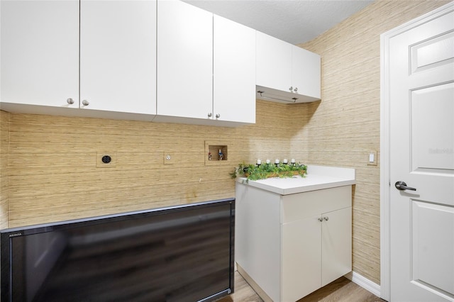 washroom featuring hookup for a washing machine, light wood-type flooring, electric dryer hookup, and cabinets