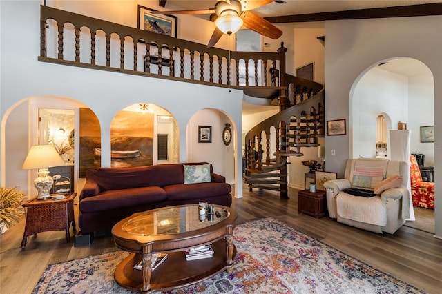 living room featuring ceiling fan, a towering ceiling, and dark hardwood / wood-style flooring