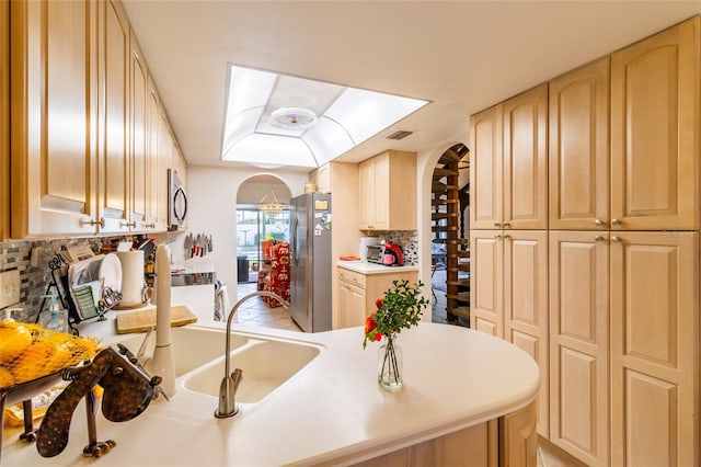 kitchen with light tile patterned floors, light brown cabinets, appliances with stainless steel finishes, and tasteful backsplash