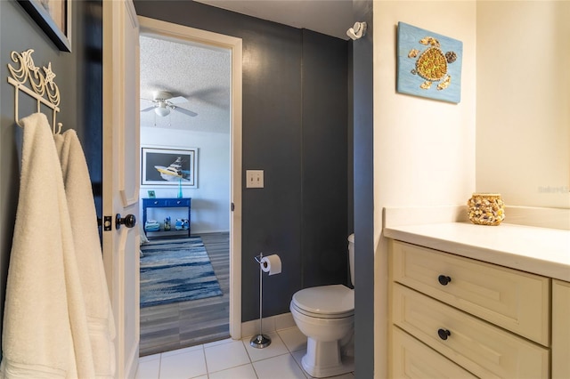 bathroom with toilet, tile patterned floors, vanity, a textured ceiling, and ceiling fan