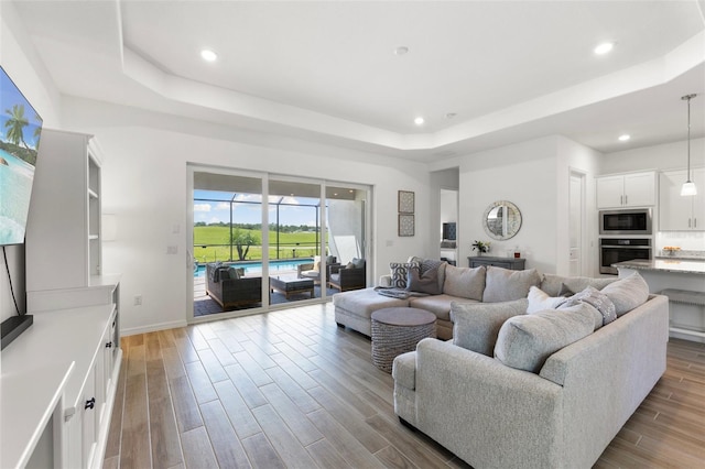 living room with light hardwood / wood-style flooring and a tray ceiling