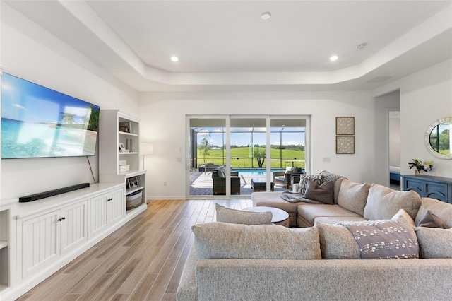 living room featuring light hardwood / wood-style floors and a tray ceiling