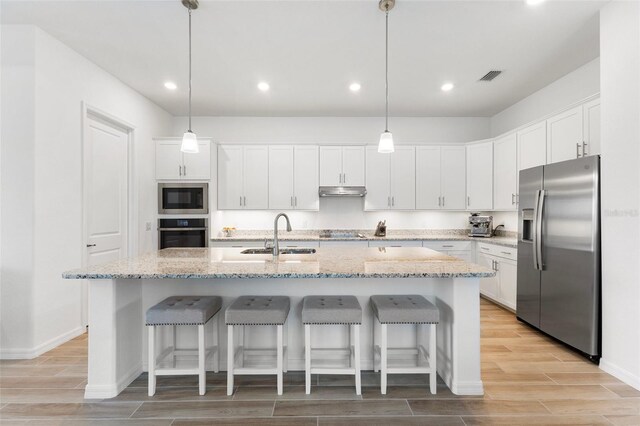 kitchen featuring stainless steel appliances, light hardwood / wood-style floors, a kitchen island with sink, and sink