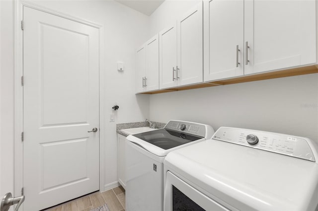 clothes washing area featuring sink, cabinets, and independent washer and dryer