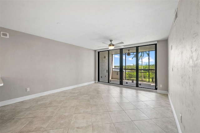 tiled spare room featuring expansive windows and ceiling fan