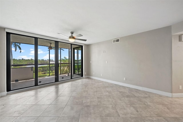 tiled spare room featuring a wall of windows, a healthy amount of sunlight, and ceiling fan