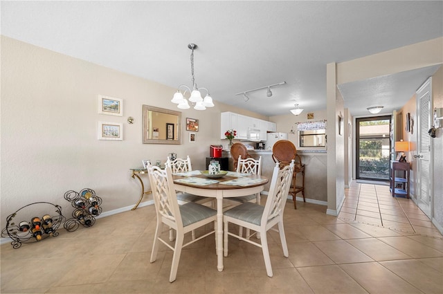 dining area with an inviting chandelier, track lighting, and light tile patterned floors