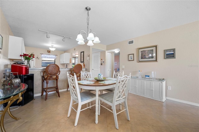 dining space with light tile patterned floors, rail lighting, and a chandelier