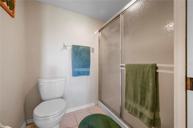 bathroom with a shower with shower door, tile patterned floors, and toilet