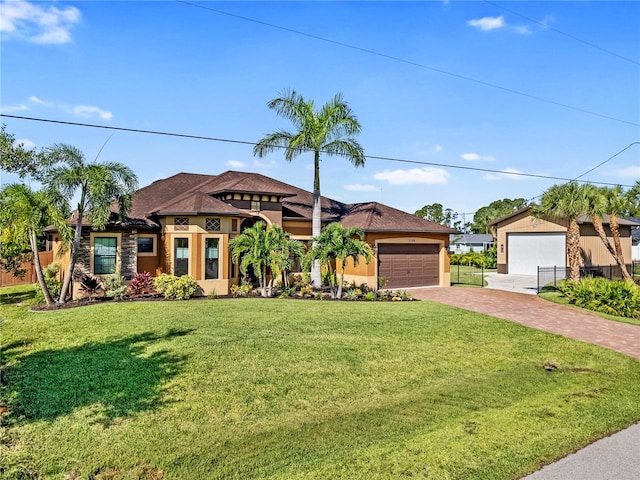 view of front of property featuring an attached garage, stucco siding, fence, and a front yard