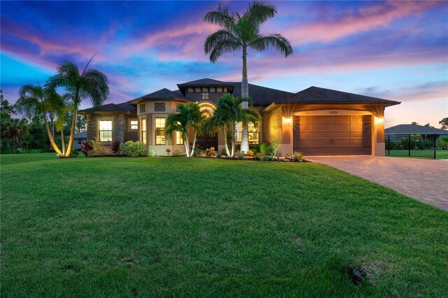 view of front facade featuring an attached garage, fence, decorative driveway, and a yard