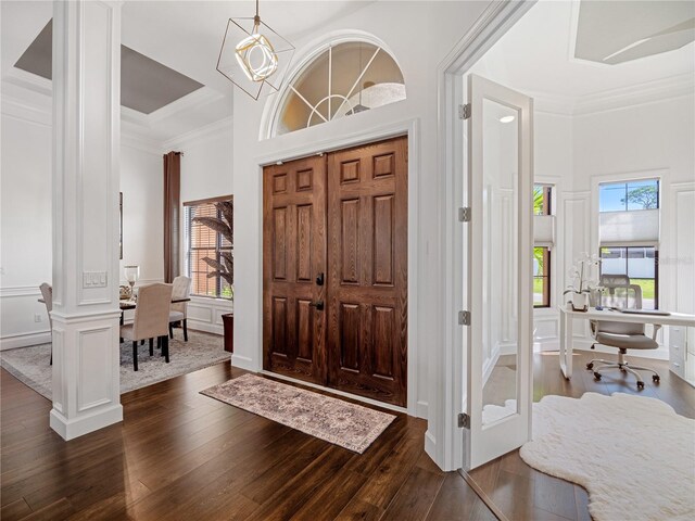 foyer entrance featuring ornamental molding, dark wood-style flooring, decorative columns, and a decorative wall