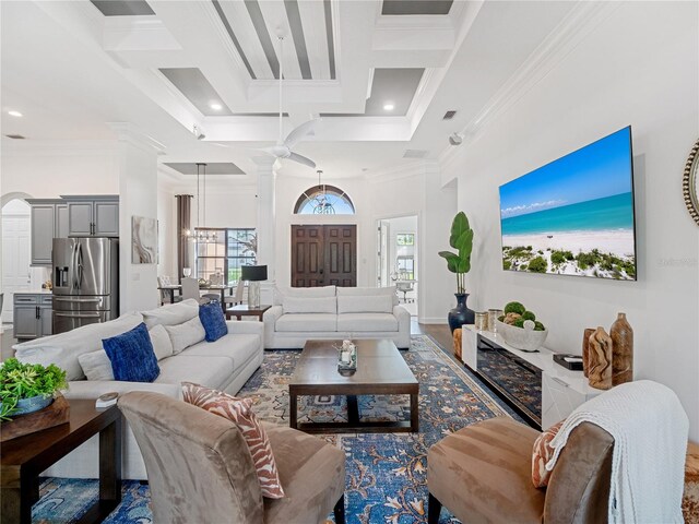 living area with plenty of natural light, coffered ceiling, a towering ceiling, and crown molding