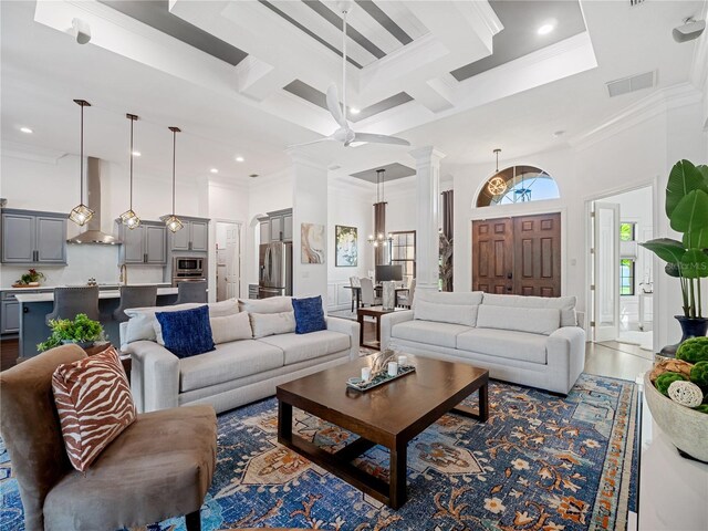 living area with ornamental molding, coffered ceiling, a towering ceiling, and ornate columns