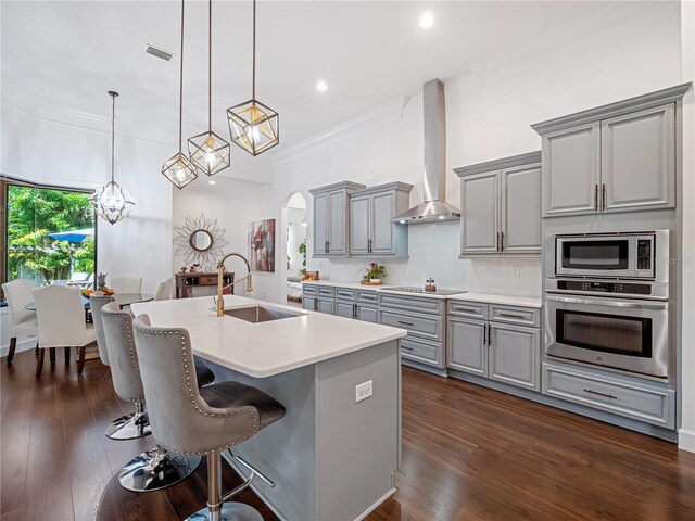 kitchen featuring wall chimney exhaust hood, decorative light fixtures, stainless steel appliances, light countertops, and gray cabinetry