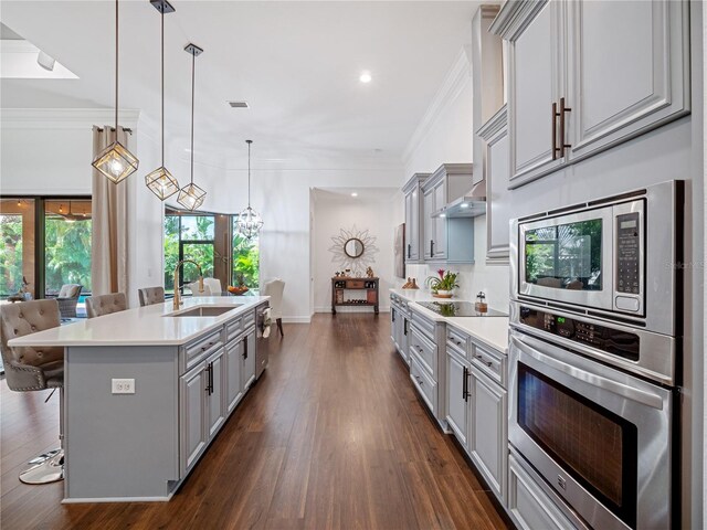 kitchen featuring stainless steel appliances, a sink, a kitchen breakfast bar, light countertops, and decorative light fixtures