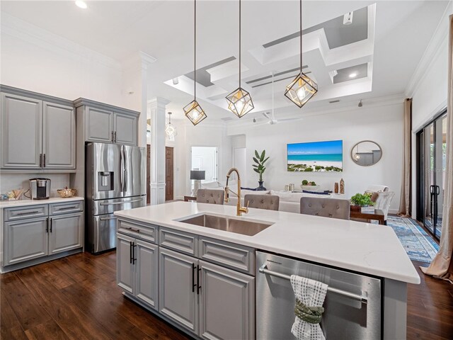 kitchen featuring open floor plan, gray cabinets, stainless steel appliances, pendant lighting, and a sink