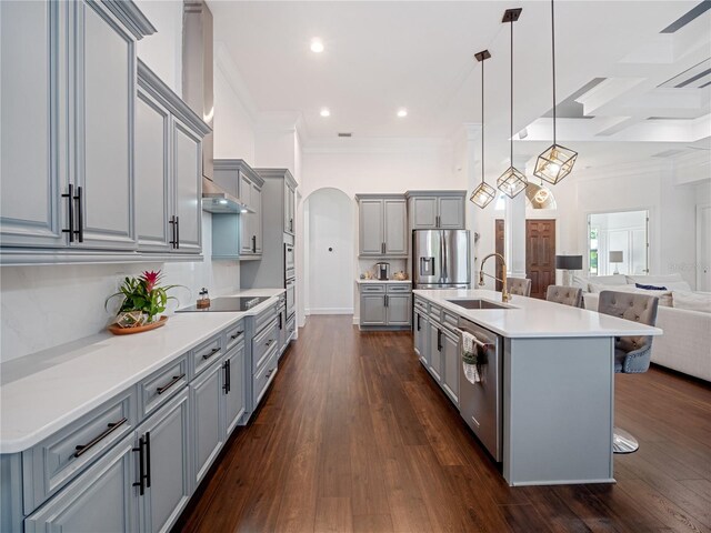 kitchen featuring stainless steel appliances, open floor plan, a kitchen island with sink, and hanging light fixtures