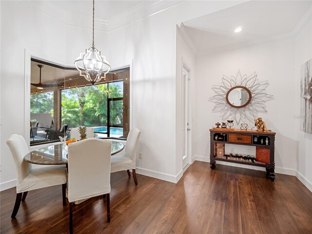 dining area featuring a notable chandelier, baseboards, wood finished floors, and crown molding