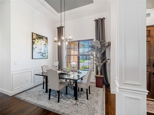 dining area with dark wood-type flooring, a tray ceiling, a notable chandelier, and a decorative wall