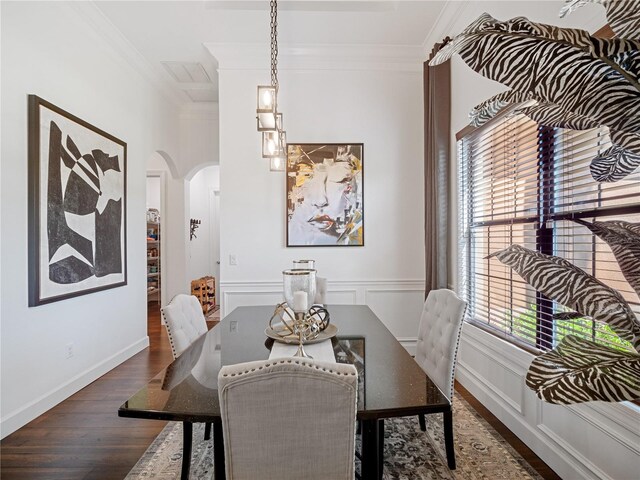 dining room with arched walkways, dark wood finished floors, crown molding, and a decorative wall