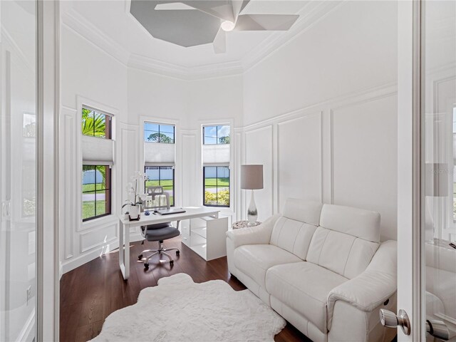 office area with dark wood-style floors, a ceiling fan, a decorative wall, and crown molding