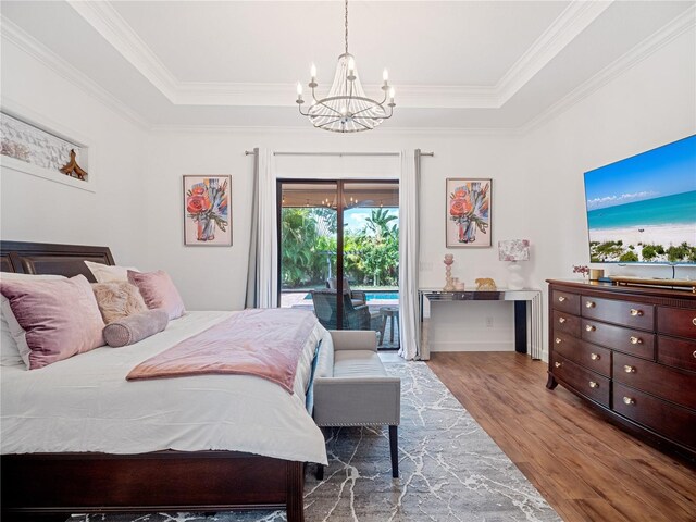 bedroom with a notable chandelier, wood finished floors, access to exterior, ornamental molding, and a raised ceiling