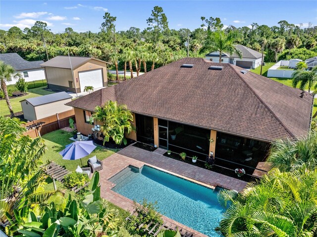 back of house featuring a patio, a shingled roof, a garage, a fenced backyard, and an outdoor pool