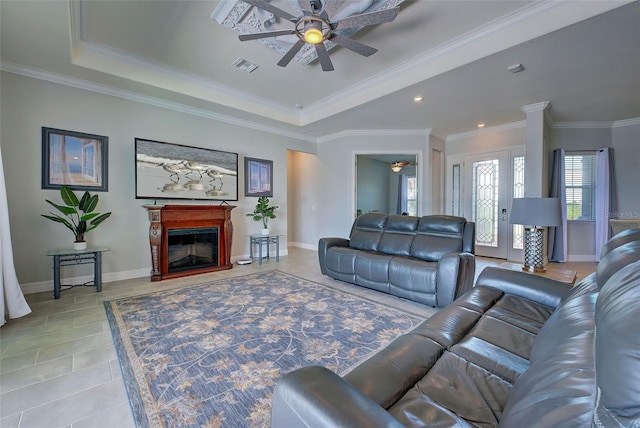 living room with crown molding, ceiling fan, a raised ceiling, and light tile patterned floors