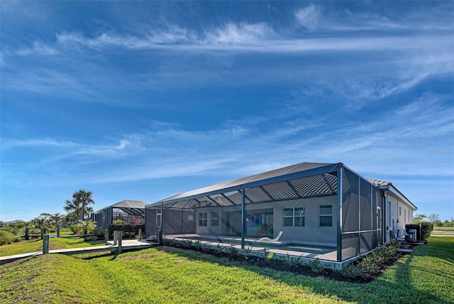 rear view of property featuring a patio area, glass enclosure, and a lawn