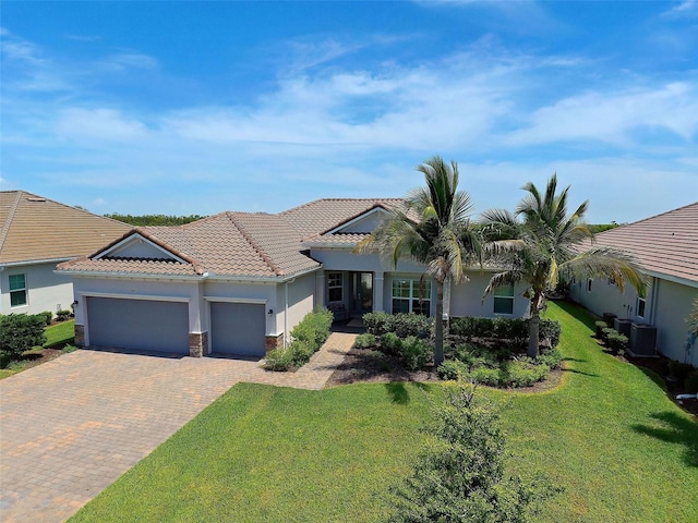 view of front of home featuring a garage, central AC, and a front yard