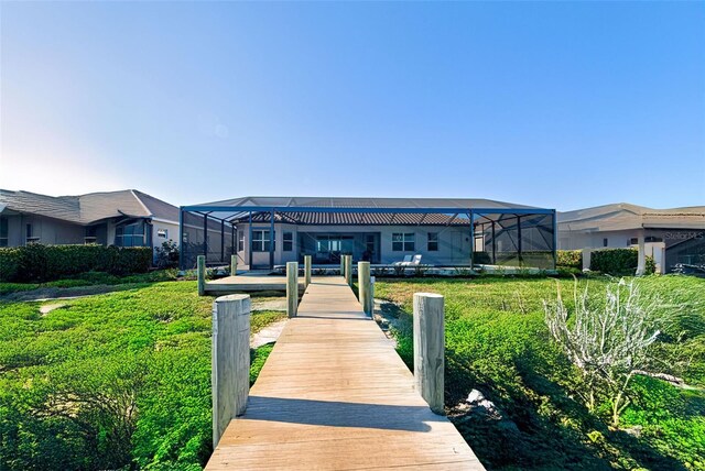 rear view of house featuring a lanai and a lawn